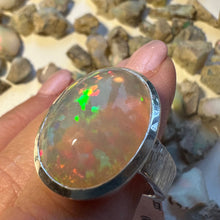 Load image into Gallery viewer, Opal ring held in a hand with a natural stone background