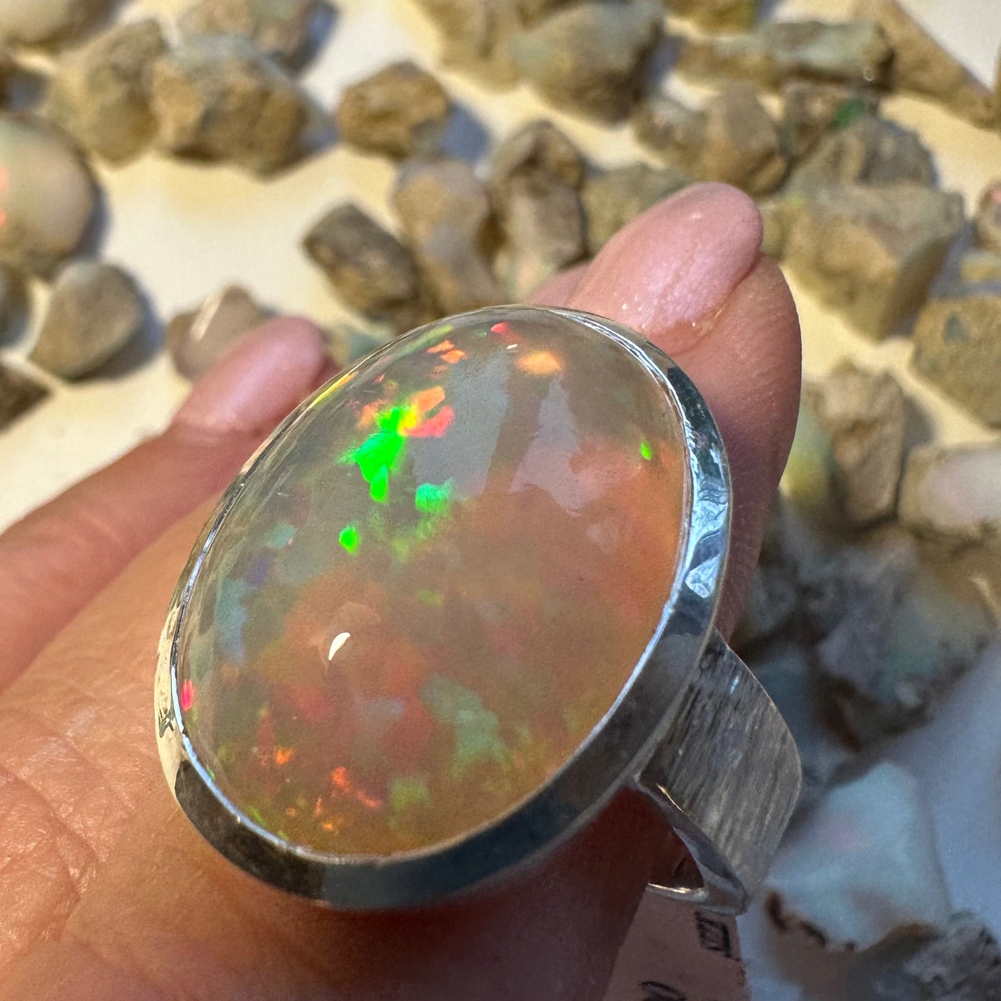 Opal ring held in a hand with a natural stone background