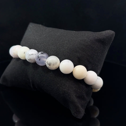 A bracelet with a series of beads on a dark background, the beads appear to be of different colors including purple and white.