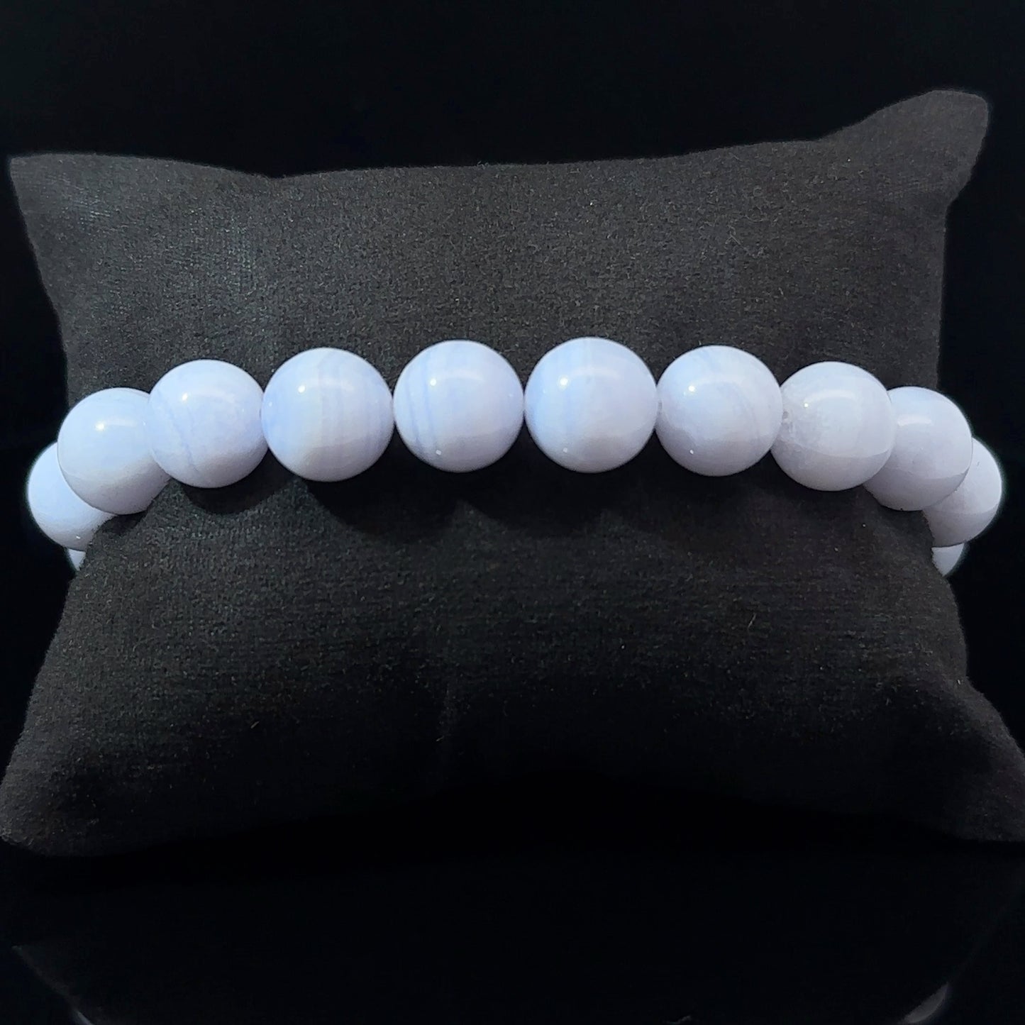 A bracelet with white and blue agate beads, displayed on a dark background