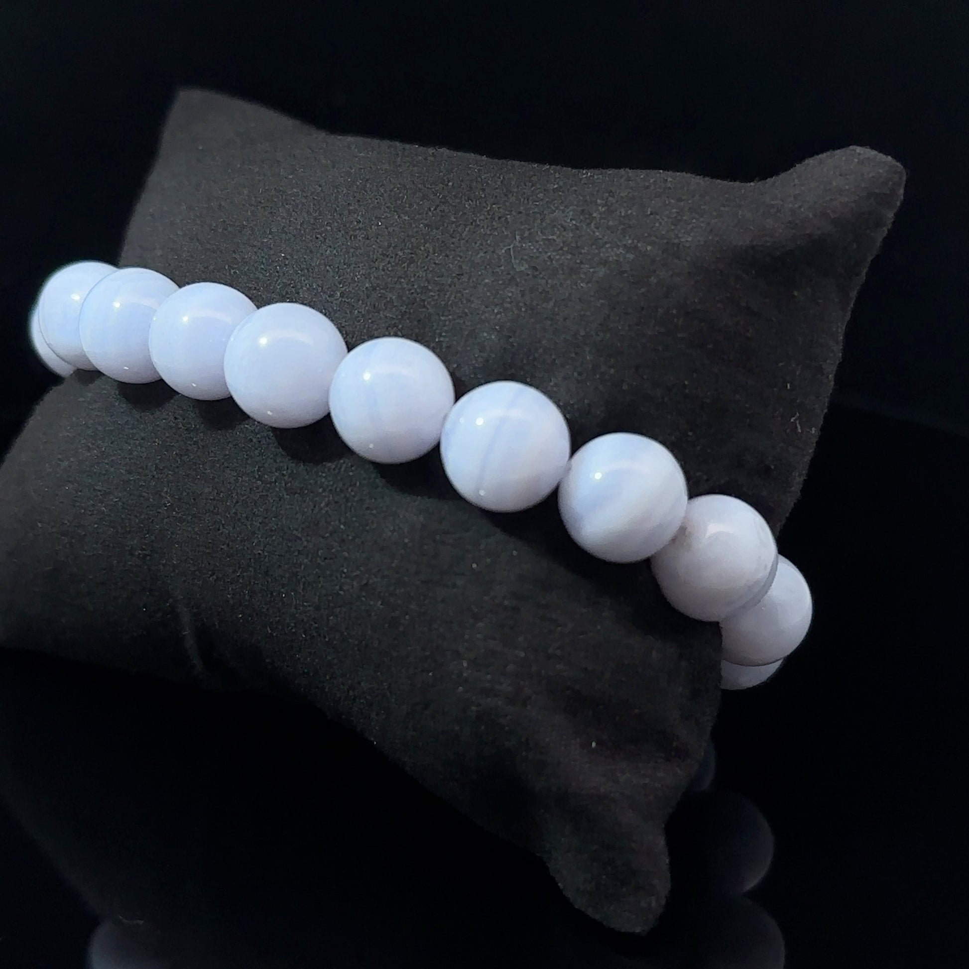 A bracelet with white and blue agate beads, displayed on a dark background, with a total of 29 beads.